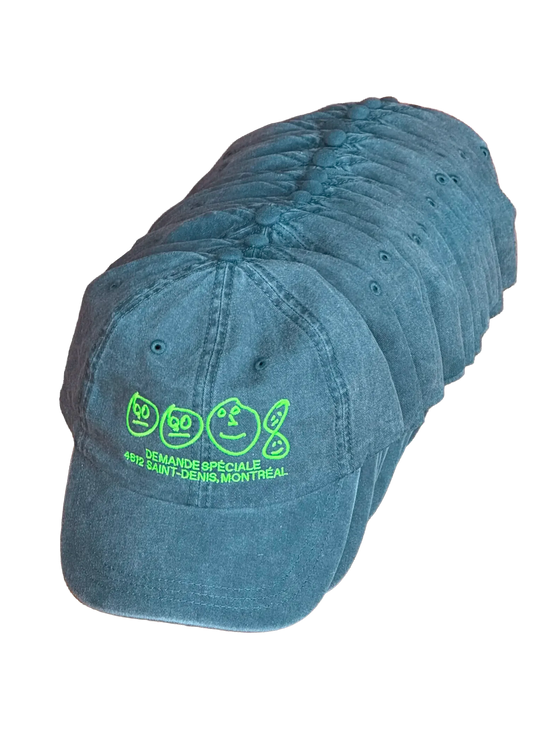 Pile de casquettes bleu-vertes Demande Spéciale, broderie vert fluo, sur fond noir