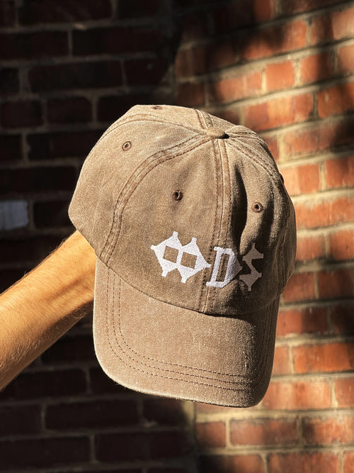Casquette kaki à logo OODS brodé blanc, tenue devant un mur de brique   (Casquette OODS 8e anniversaire)