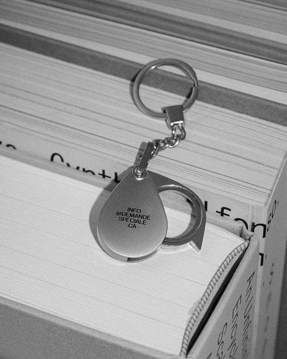 Porte-clé loupe gravé posé sur les pages d'un livre, photo noir et blanc