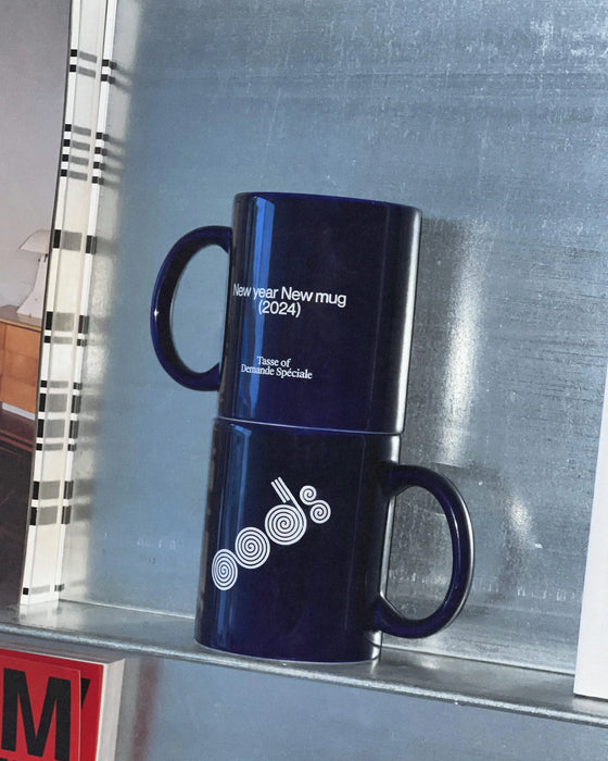 Deux tasses bleu marine OODS empilées, « New year New mug (2024) » et logo, sur tablette