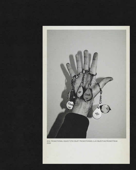 Main ouverte présentant des porte-clés loupe et objets promotionnels, photo noir et blanc