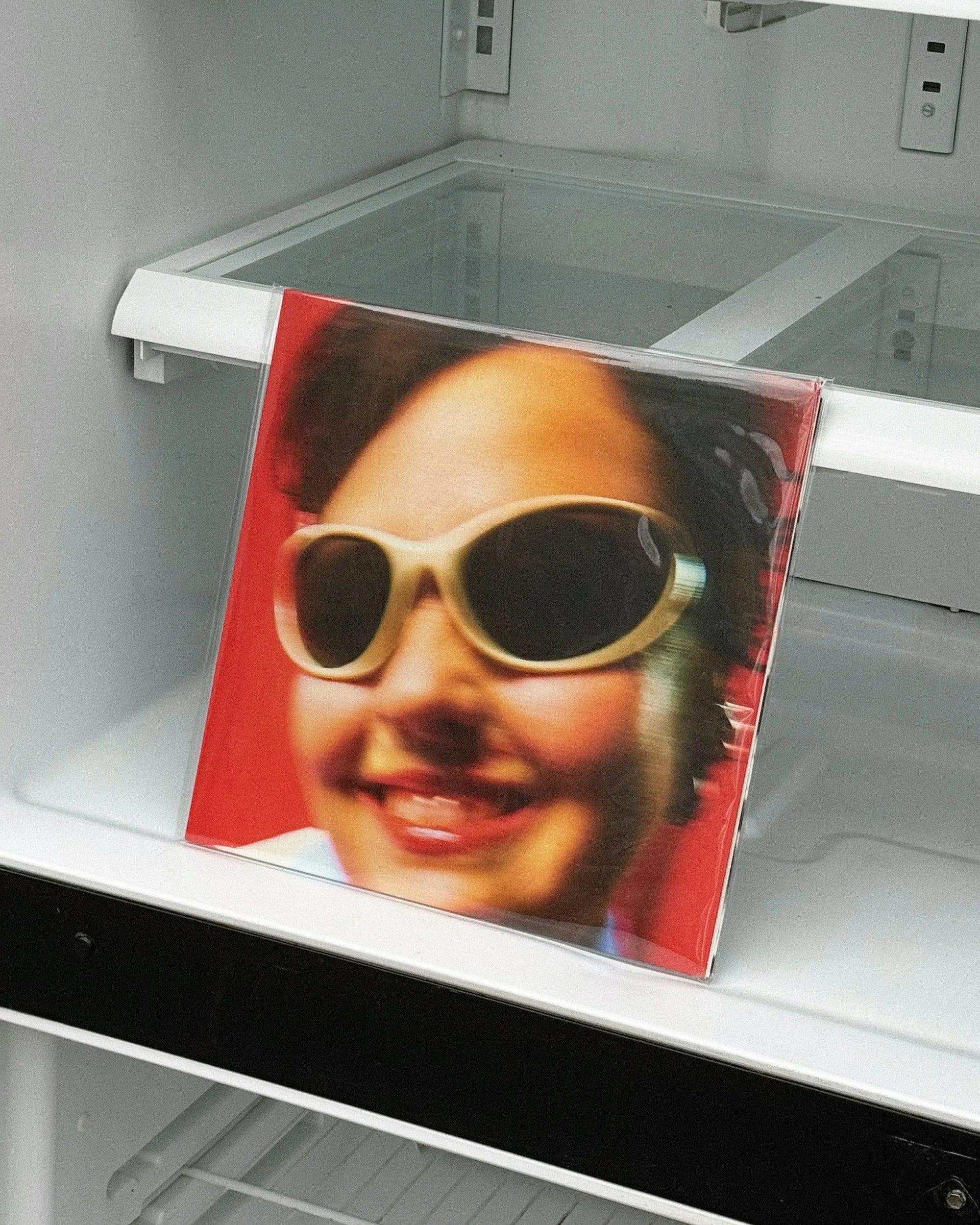 Airs de Jeux — pochette rouge posée dans un réfrigérateur, portrait souriant à lunettes blanches