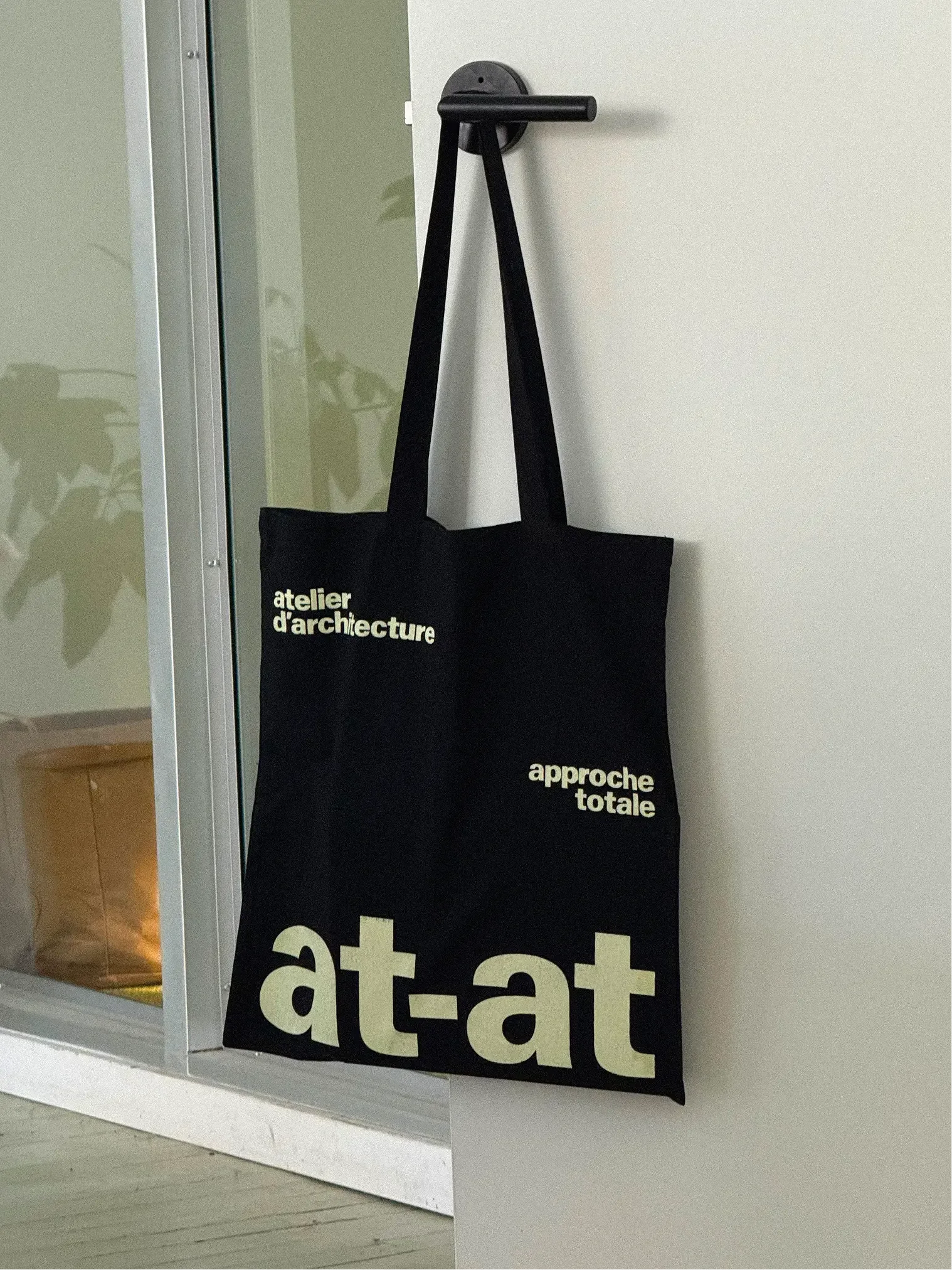 at-at — sac tote noir suspendu, logo et signature en blanc et jaune