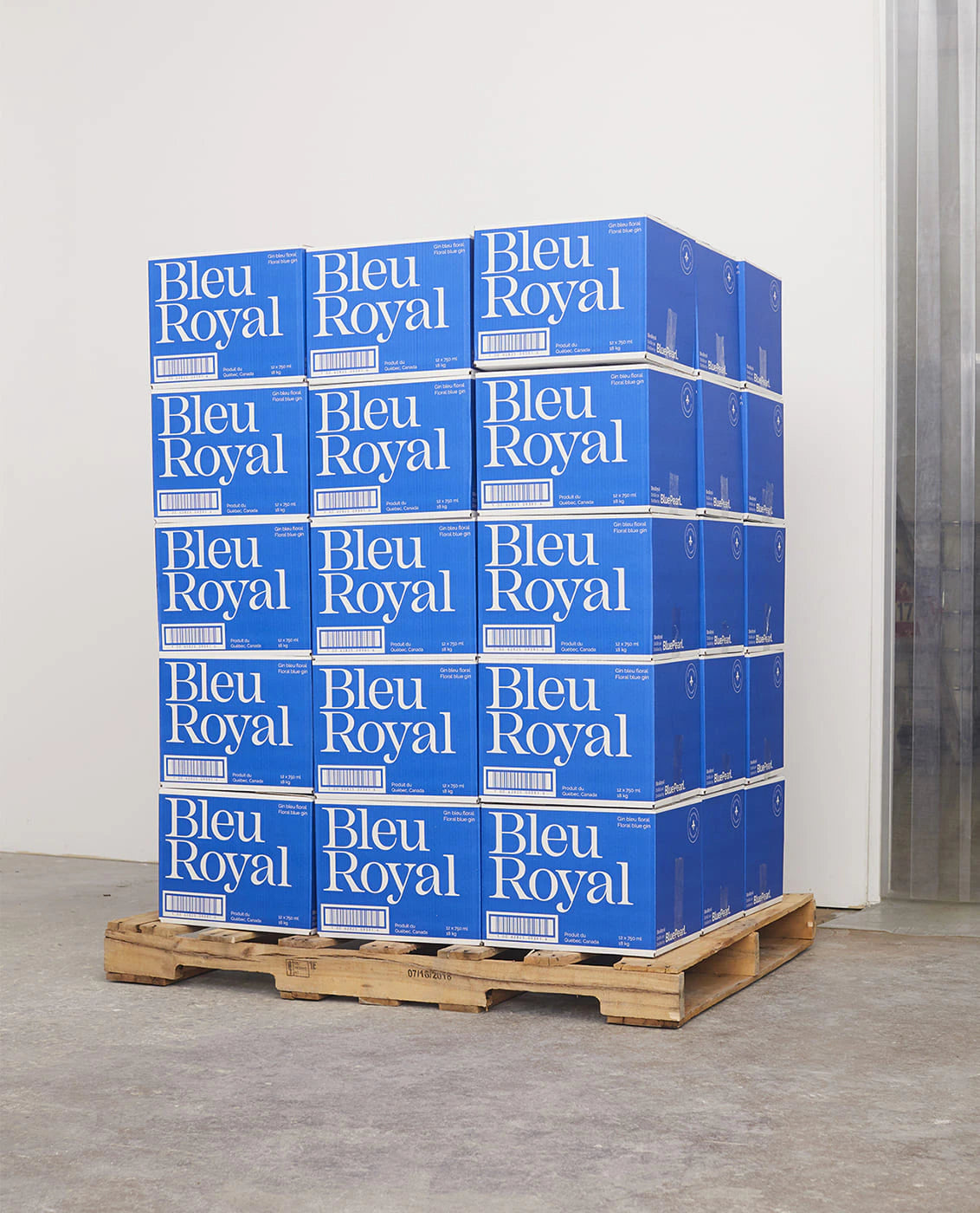 BleuRoyal — palette de caisses bleues du gin empilées dans un entrepôt