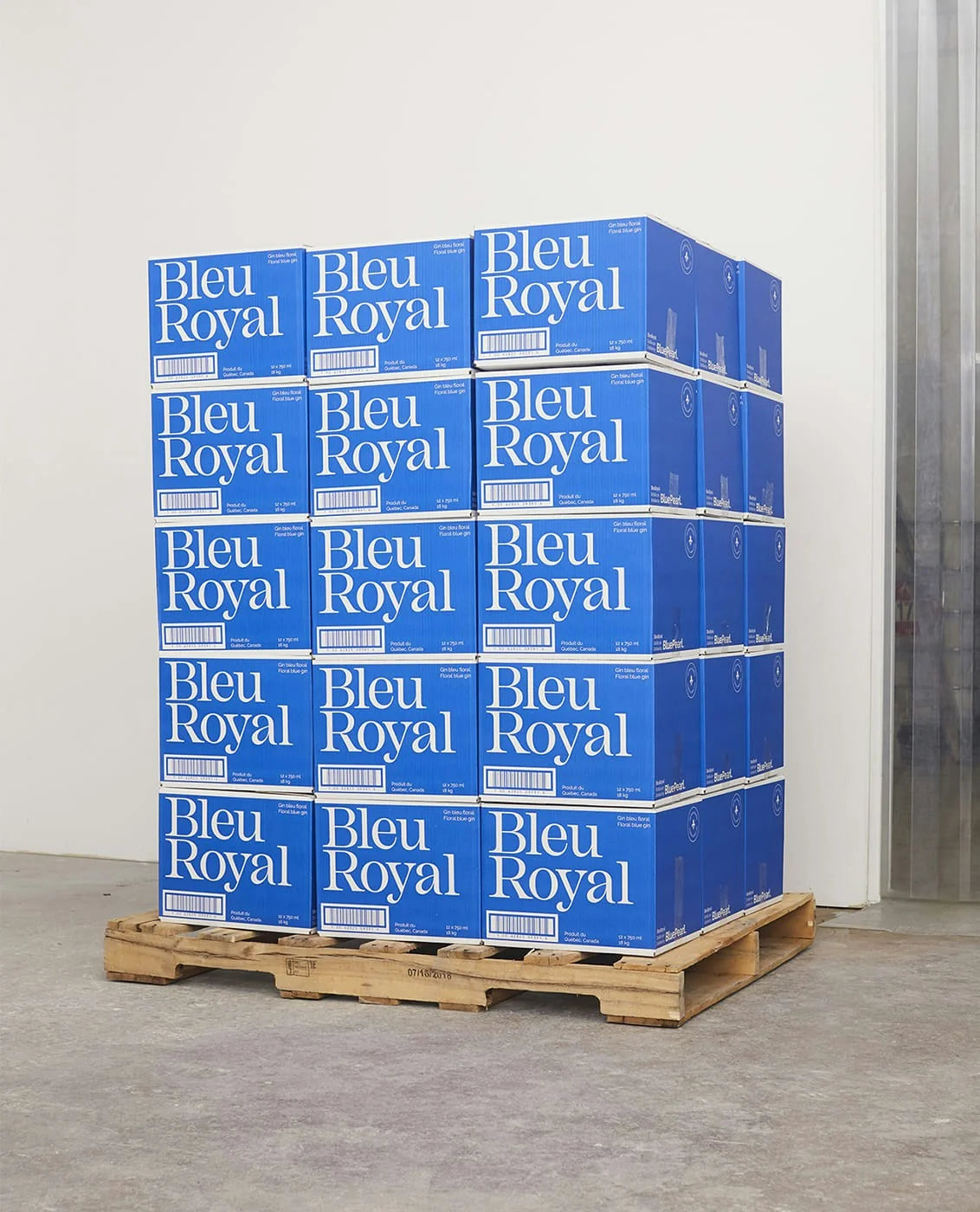BleuRoyal — palette de caisses bleues du gin empilées dans un entrepôt