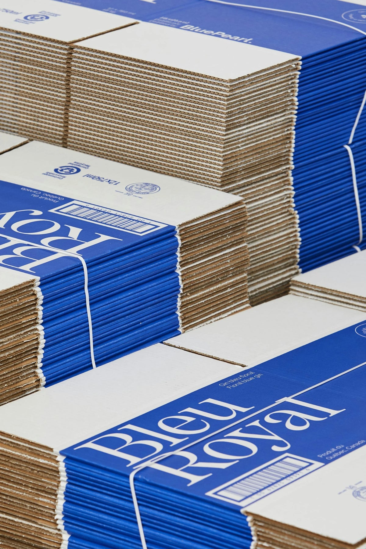 BleuRoyal — piles d'emballages de gin imprimés au wordmark bleu et blanc en atelier