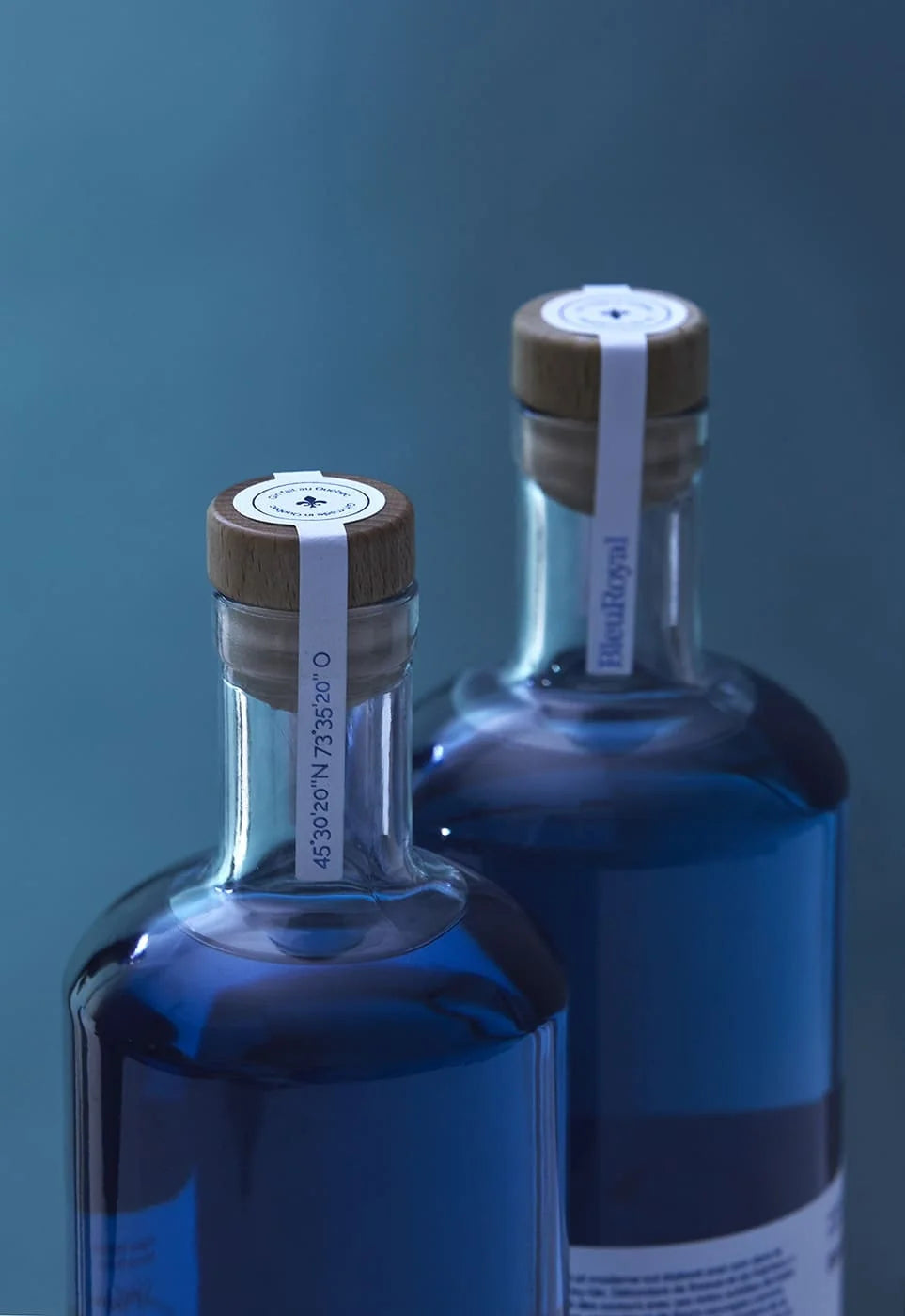 BleuRoyal — deux bouteilles de gin bleu à bouchon liège, scellées, fond bleu studio