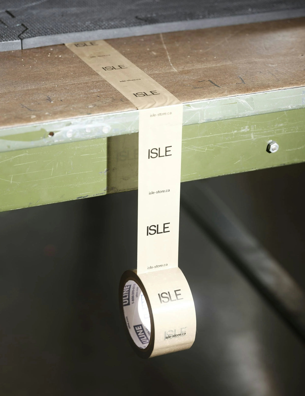ISLE — rouleau de ruban adhésif imprimé « ISLE » se déroulant sous un plan de travail