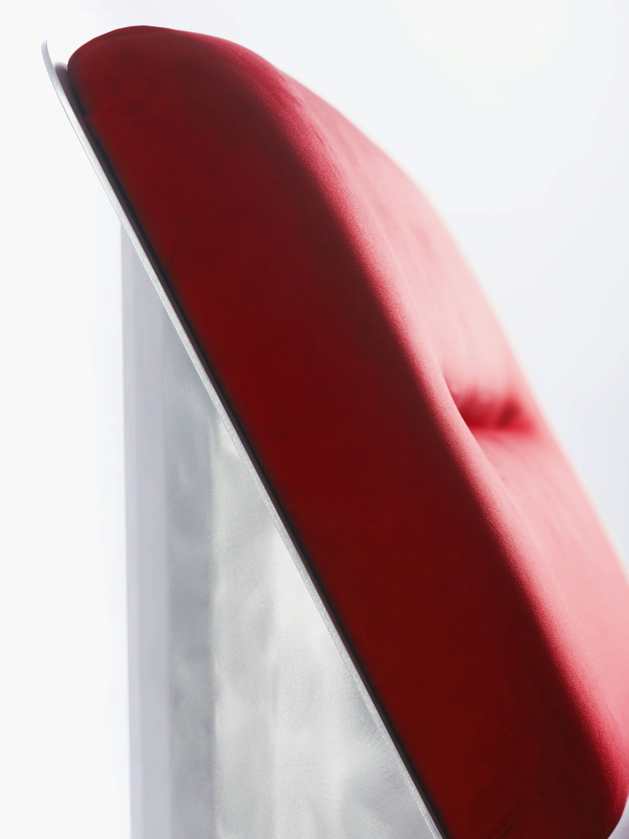 ISLE — détail d'une assise capitonnée rouge sur structure métallique, vue rapprochée