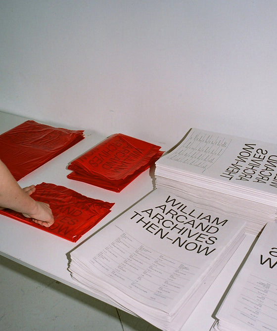 Mains feuilletant les pages rouges du journal William Arcand