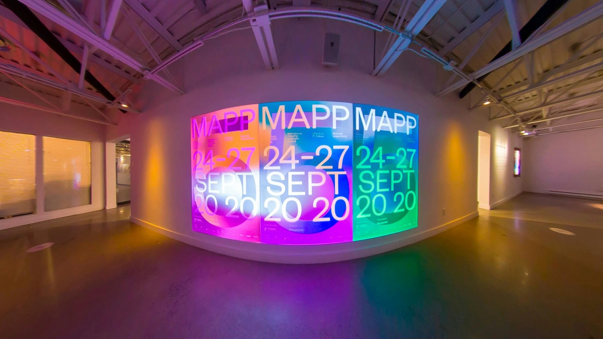 L'inconnu — installation de mapping vidéo projetant l'affiche aux dégradés colorés sur un mur de galerie