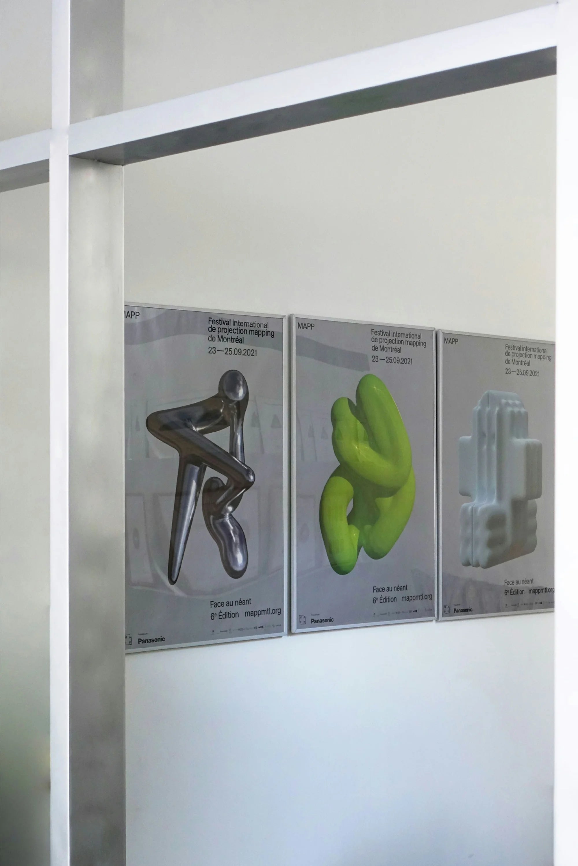 Face au néant — trois affiches encadrées exposées au mur, sculptures 3D argentée, verte et blanche