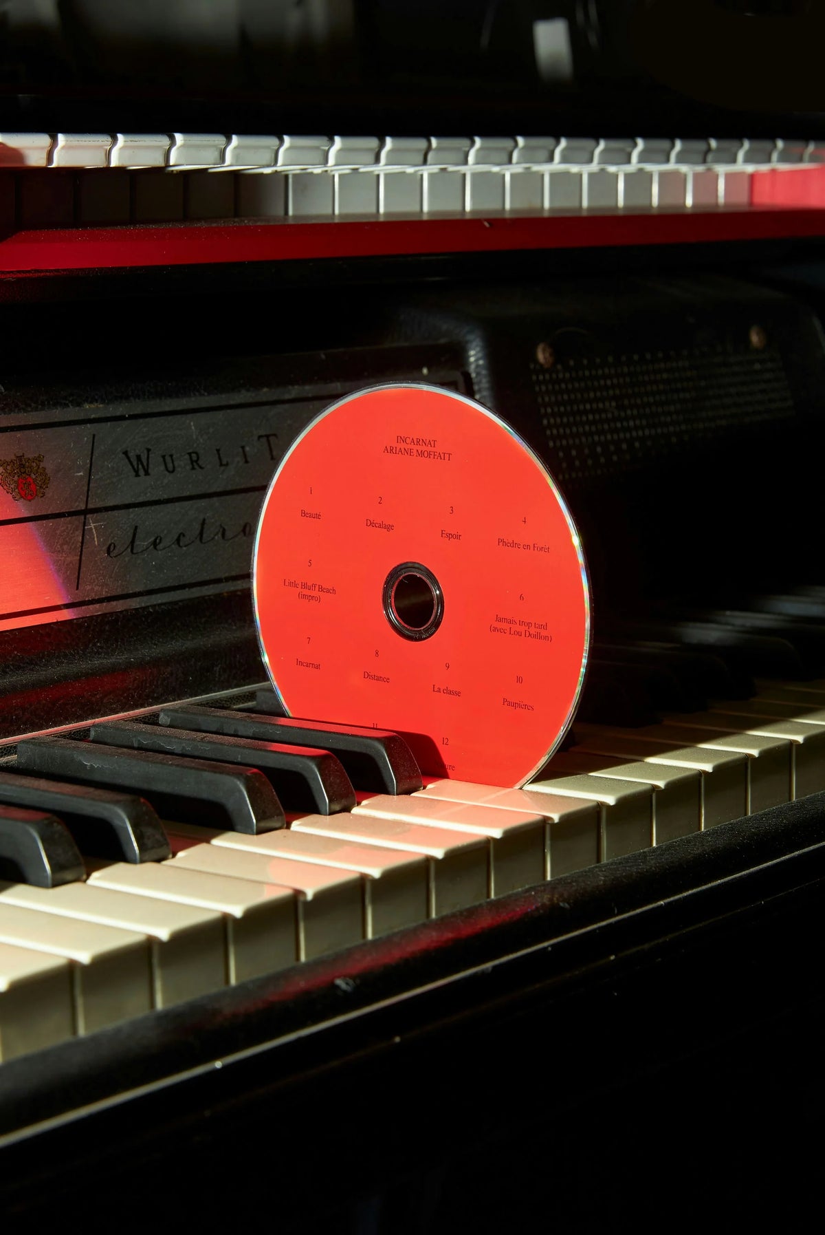 Ariane Moffatt — disque CD rouge d'Ariane Moffatt posé sur les touches d'un piano