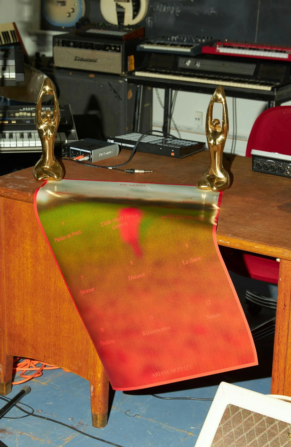 Ariane Moffatt — affiche rouge incurvée d'Ariane Moffatt posée sur une table en bois