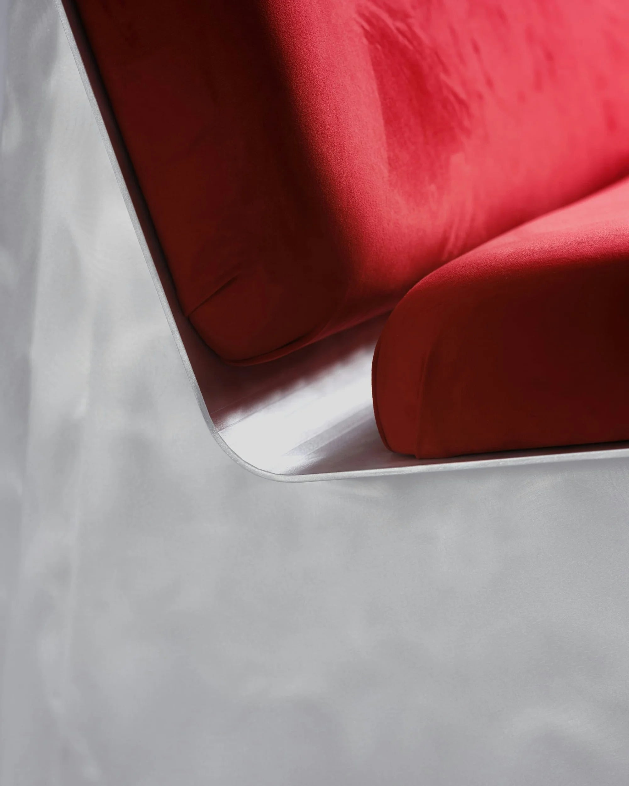 SANGARE — gros plan d'une banquette à coussins rouges sur structure métallique chromée, fond gris