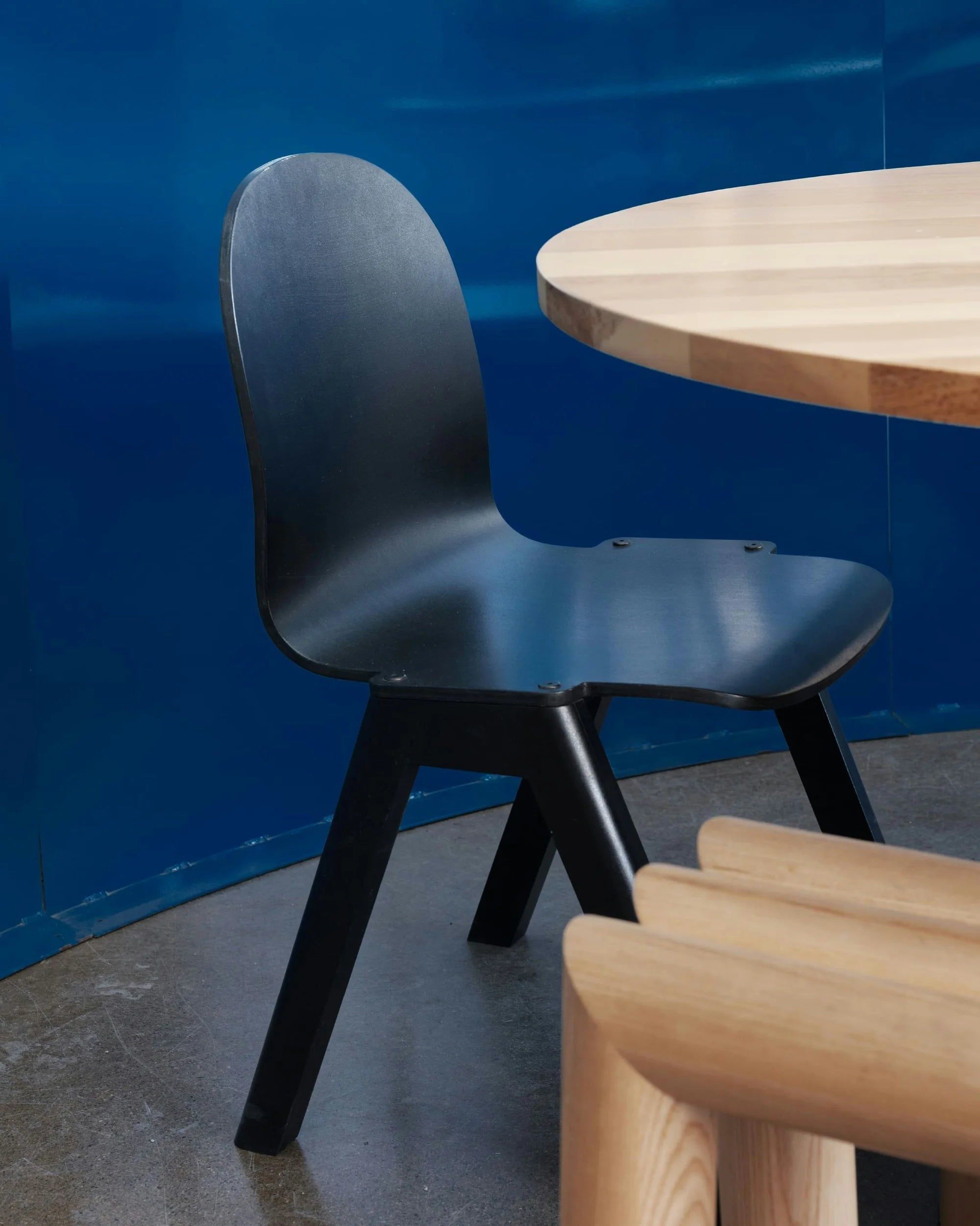 SANGARE — chaise noire en bois courbé près d'une table en bois clair, mur bleu laqué