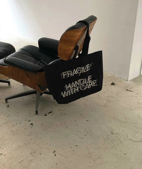 Tote bag Fragile Handle With Care posé sur une chaise Eames