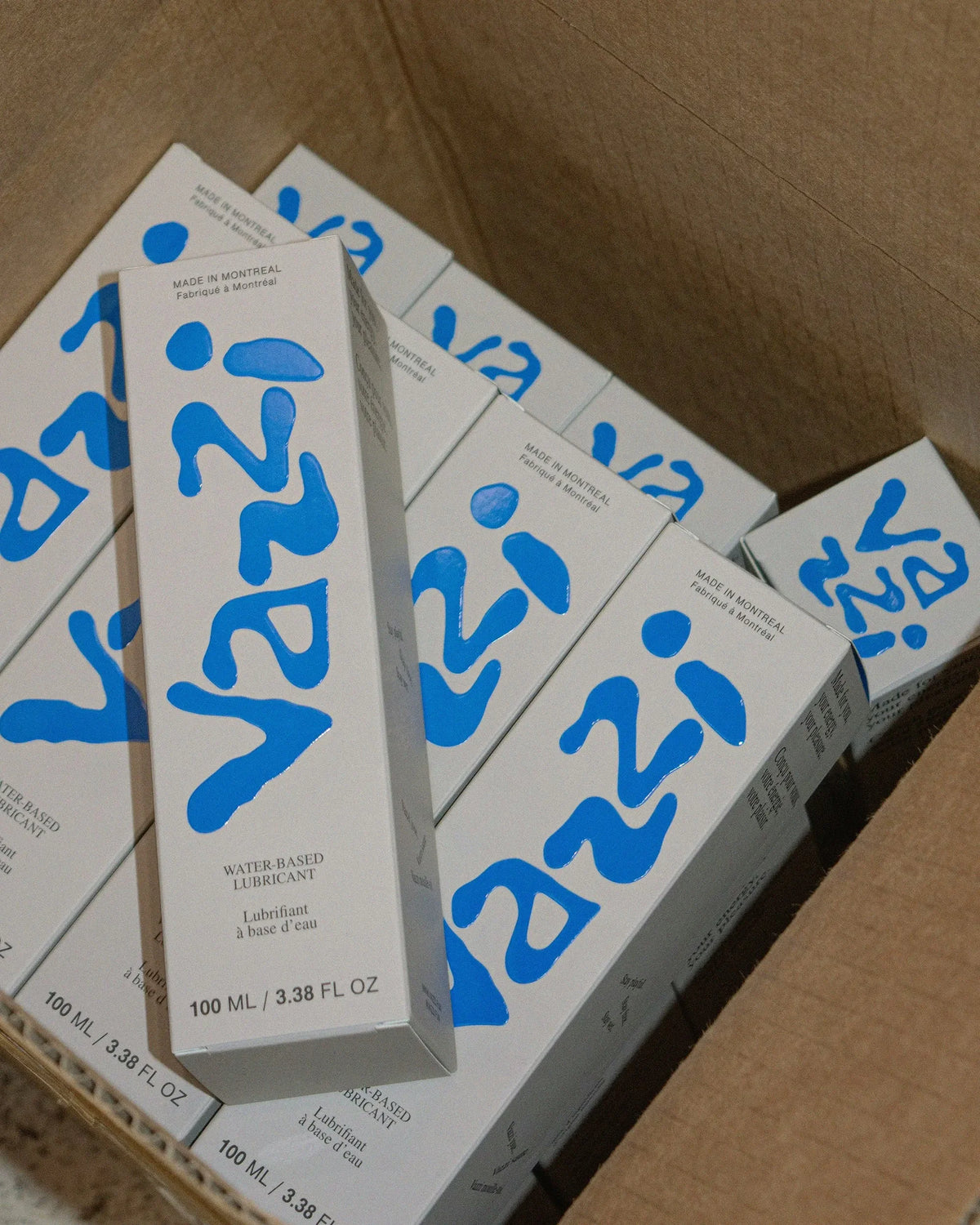 Vazzi — boîte ouverte remplie d'étuis de lubrifiant au logo bleu manuscrit