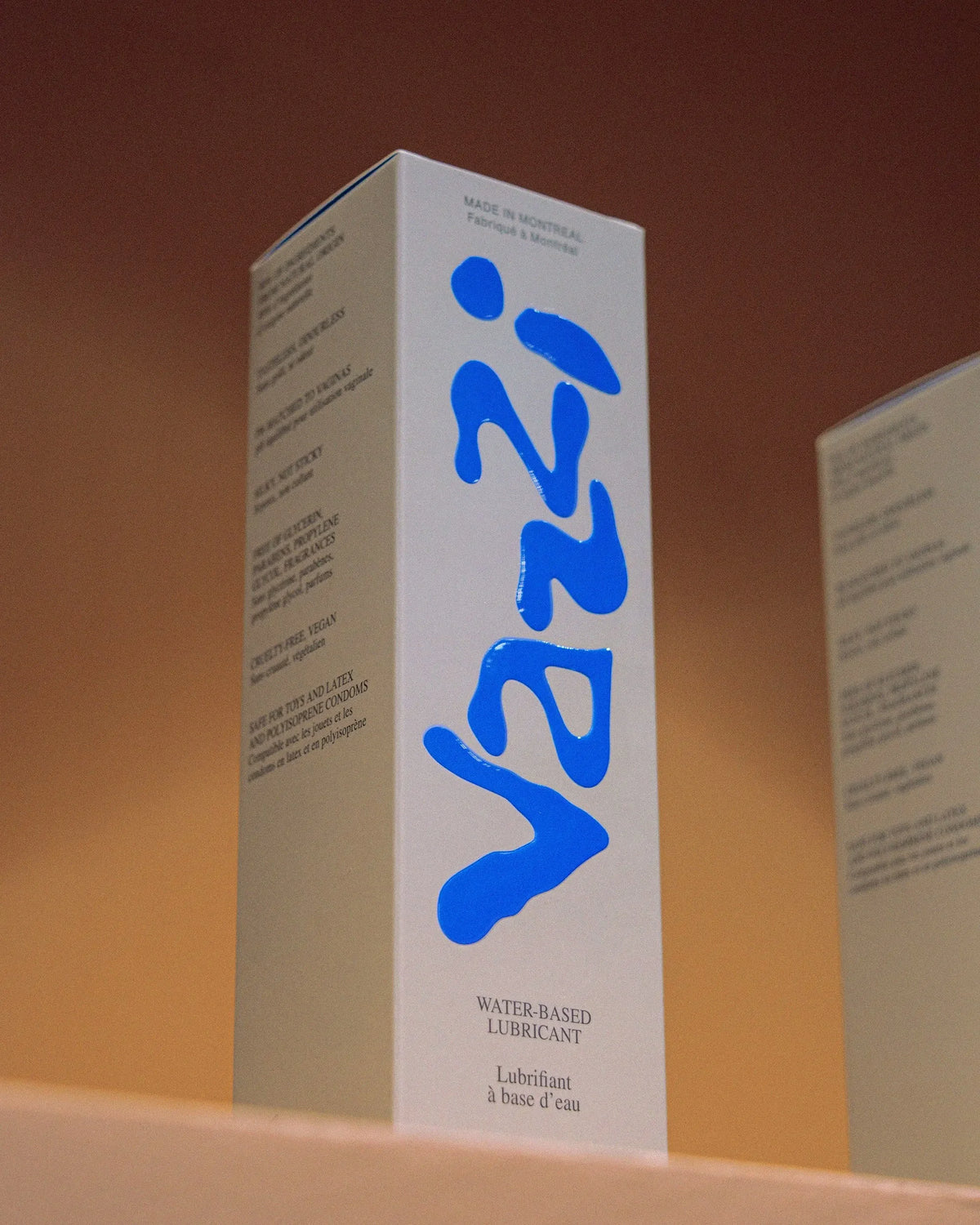 Vazzi — étui vertical au logo bleu manuscrit posé sur fond orange dégradé
