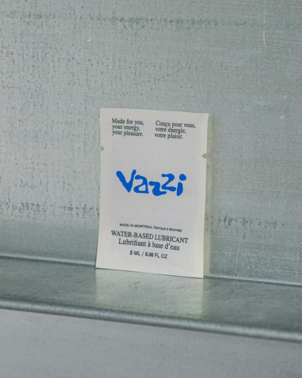 Vazzi — sachet échantillon de lubrifiant au logo bleu sur tablette métallique