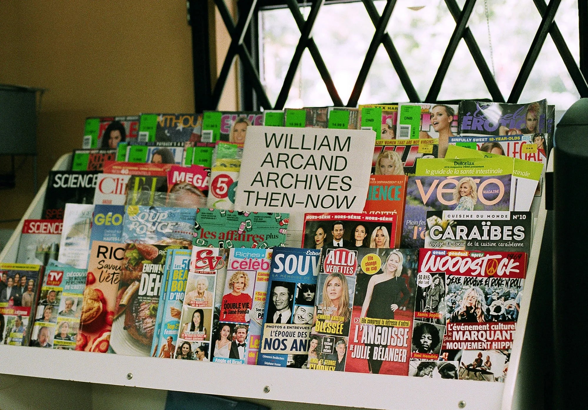 Then-Now — présentoir de magazines avec carton imprimé « William Arcand Archives Then-Now » au centre