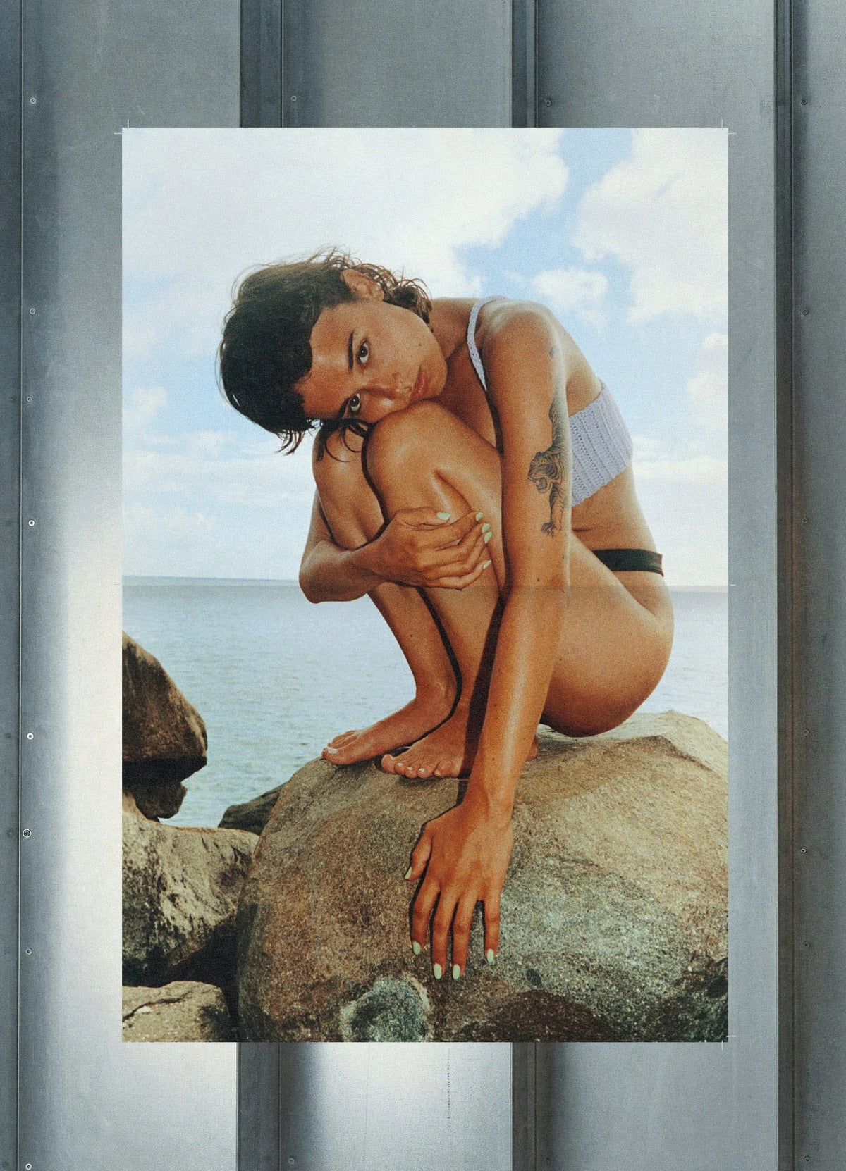 Now — affiche photo couleur d'une femme accroupie sur un rocher au bord de la mer